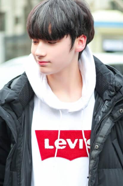 Huening Kai wallpapers shows a young man wearing a white Levi's hoodie and black jacket, HD Phone Wallpaper