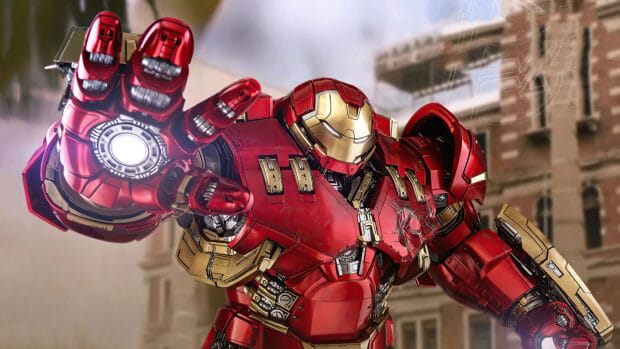 The Hulkbuster suit is shown extending its hand in front of a city building, 4K Desktop Wallpaper