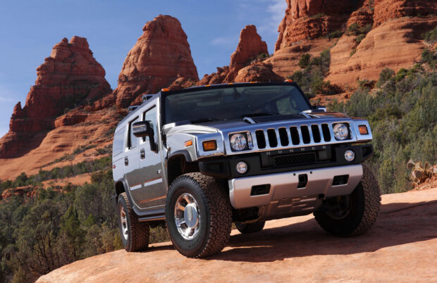 A silver Hummer H3 is parked in a rocky desert with red cliffs in the background, HD Desktop Wallpaper