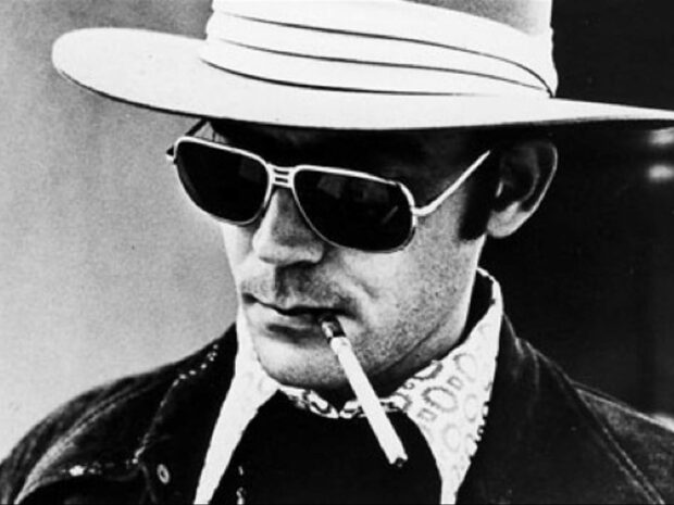 Hunter S Thompson is wearing sunglasses and a hat while smoking a cigarette, HD Desktop Wallpaper