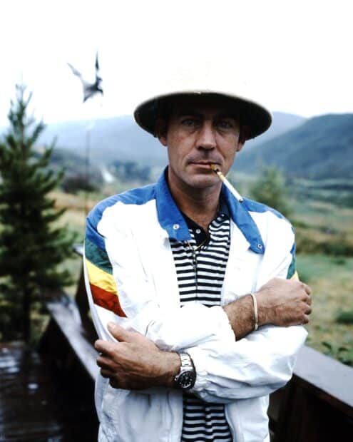 Hunter S Thompson is standing confidently outdoors wearing a striped shirt and a hat, HD Mobile Wallpaper