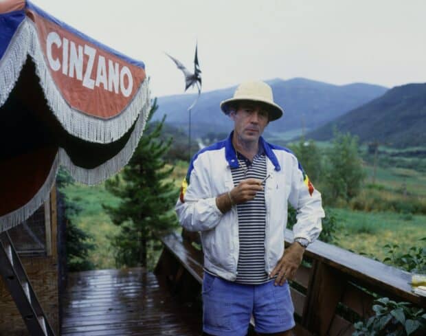 Hunter S Thompson is standing on a wooden deck with a cigarette and scenic hills in the background, HD Desktop Wallpaper