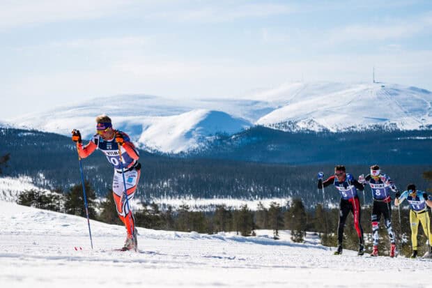 Iivo Niskanen skiing through a snowy landscape with other competitors in the background, HD Desktop Wallpaper