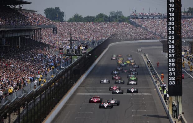 The Indianapolis Motor Speedway is filled with racing cars and a large crowd during the race start, 2K Desktop Wallpaper
