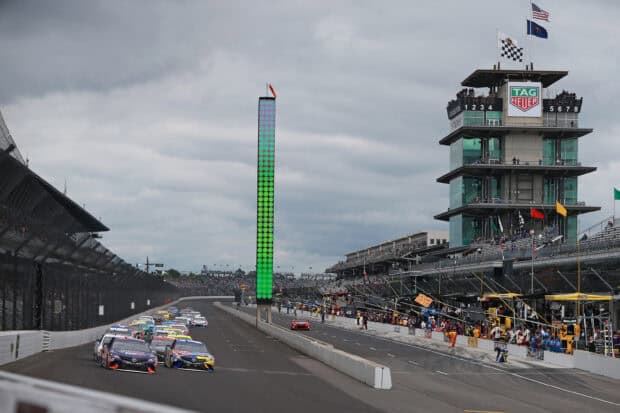 A NASCAR race takes place at Indianapolis Motor Speedway with cars speeding on the track, 2K Desktop Wallpaper