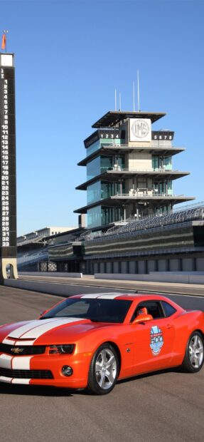 A red racing car is parked on the Indianapolis Motor Speedway track near the grandstand, 2K Mobile Wallpaper