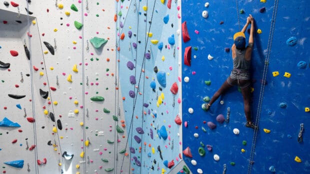A person is rock climbing on a multicolored indoor climbing wall, HD Desktop Wallpaper