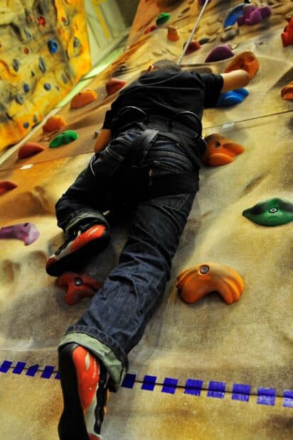 A climber uses safety gear while rock climbing an indoor wall, HD Mobile Wallpaper