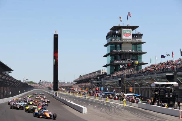 The Indianapolis Motor Speedway hosts a crowded IndyCar race with racing cars on the track, 2K Desktop Wallpaper