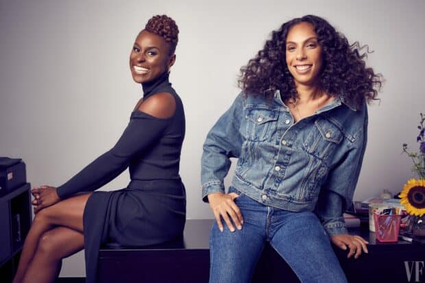 Two women from Insecure tv series are smiling and sitting together in a casual setting, HD Desktop Wallpaper