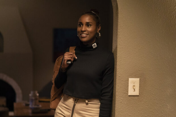 A woman from Insecure Tv Series wearing a black top and beige skirt stands indoors smiling, HD Desktop Wallpaper
