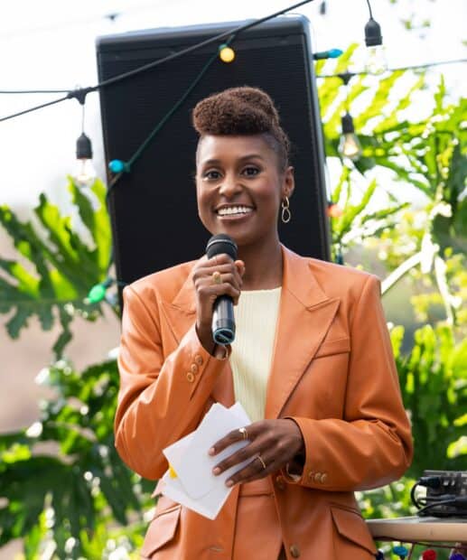 A woman from Insecure tv series is holding a microphone and notes while speaking outdoors, HD Mobile Wallpaper