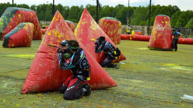 Two players hide behind inflatable bunkers in a paintball match, HD Desktop Wallpaper
