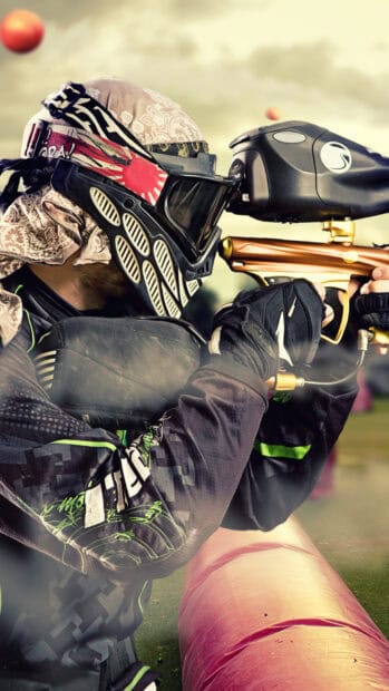 A paintball player in full gear aiming carefully during a match, HD Phone Wallpaper
