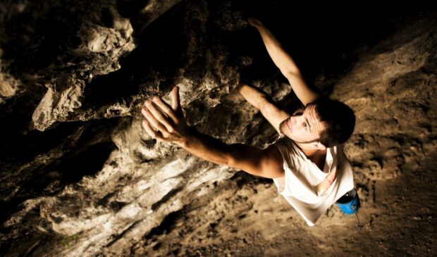 A man focused on an intense rock climbing challenge on a rugged cliff, 2K Desktop Wallpaper