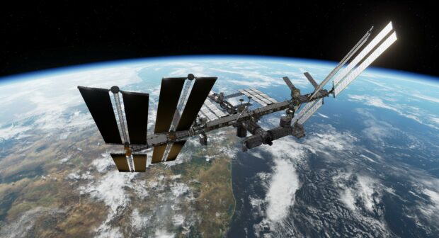 The space station is orbiting above Earth showing continents and ocean, 4K Desktop Wallpaper