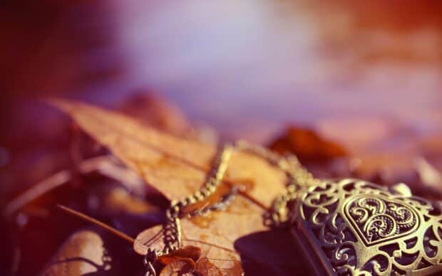 An intricate heart pendant lies on autumn leaves highlighting jewelry wallpapers, 2K Desktop Wallpaper