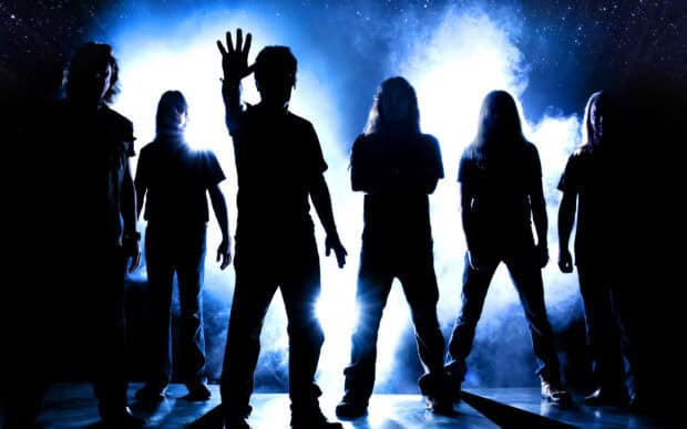 Iron Maiden band stands in front of blue smoky light with one member raising a hand, 2K Desktop Wallpaper