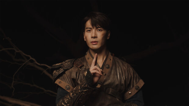 Jackson Wang in a thoughtful pose wearing traditional warrior clothing with a dark background, HD Desktop Wallpaper