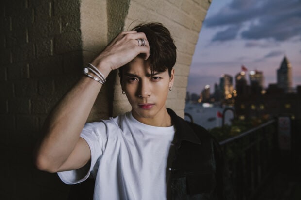 Jackson Wang Wallpapers standing near a brick wall with a city skyline at dusk, HD Desktop Wallpaper