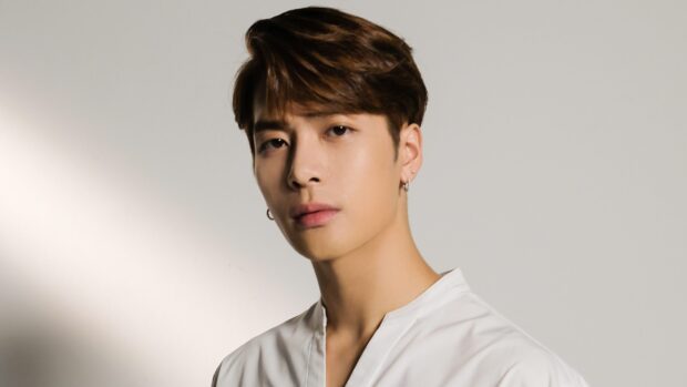 Jackson Wang Wallpapers showing a man in a white shirt with earrings against a plain background, 2K Desktop Wallpaper