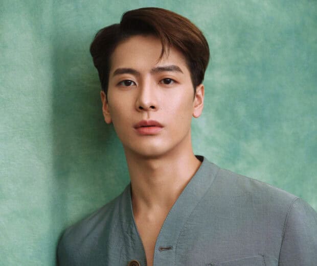 A portrait of Jackson Wang with a calm expression and green background, HD Mobile Wallpaper