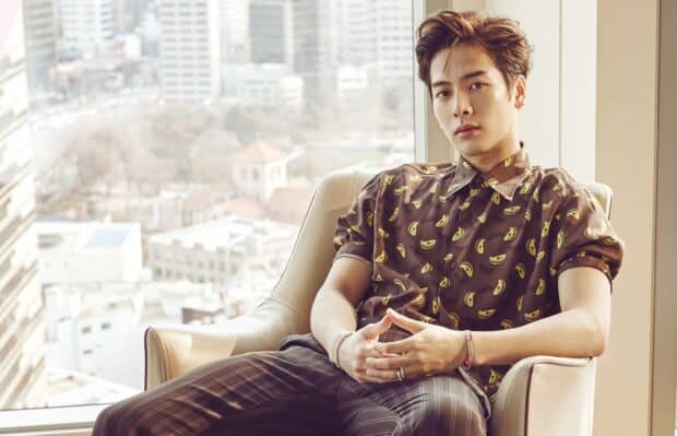 Jackson Wang is sitting calmly in a chair with a cityscape background, HD Desktop Wallpaper