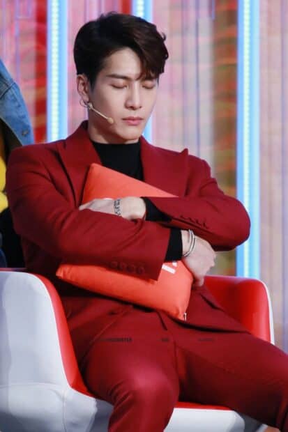 Jackson Wang sitting calmly with eyes closed and holding an orange cushion, HD Phone Wallpaper