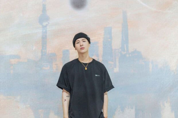 Jackson Wang stands in front of a faded city skyline mural, HD Desktop Wallpaper