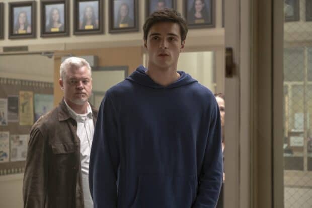 Jacob Elordi wearing a blue hoodie standing indoors with people behind him, HD Desktop Wallpaper