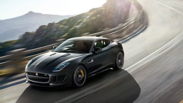 A Jaguar F Type is driving fast on a winding mountain road with sunlight shining, HD Desktop Wallpaper