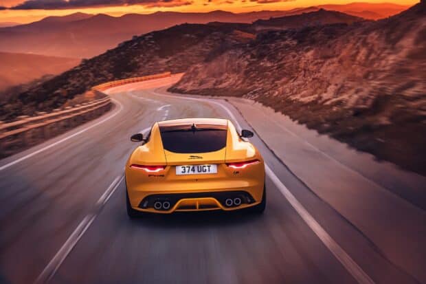 A yellow Jaguar F Type is driving along a winding mountain road during sunset, HD Desktop Wallpaper