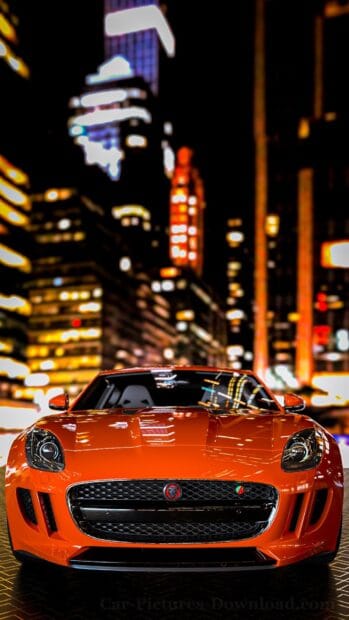 A bright orange Jaguar F Type is parked with city skyscrapers blurred in the background, HD Mobile Wallpaper