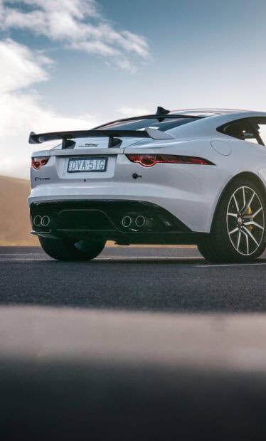 A white Jaguar F Type is parked on the asphalt road under a cloudy sky, HD Phone Wallpaper