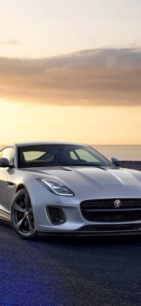 A silver Jaguar F Type sports car is parked with a sunset sky in the background, 2K Mobile Wallpaper