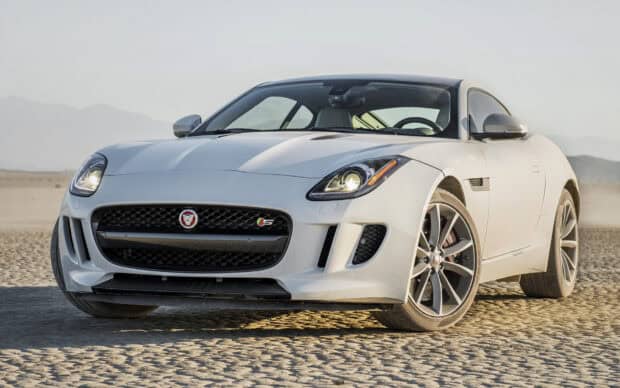 A white Jaguar F Type sports car is parked on a dry desert terrain with mountains in the background, HD Desktop Wallpaper