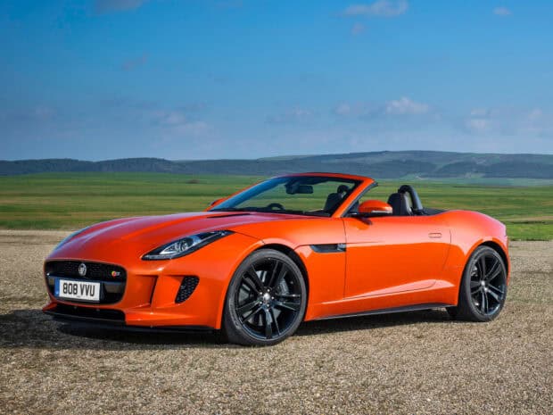 A bright orange Jaguar F Type is parked on a gravel road with green hills in the background, HD Desktop Wallpaper
