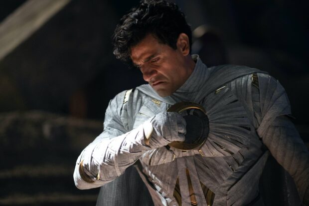 Jake Lockley in a white costume holding a circular object and looking down, 2K Desktop Wallpaper