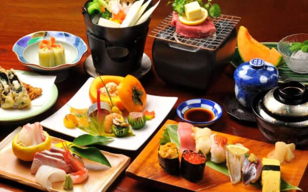 A variety of delicious Japanese dishes including sushi and grilled meat are arranged on a wooden table, 2K Desktop Wallpaper