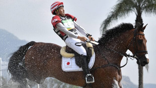 A Japanese equestrian is focused during an eventing competition with water splashing around, 4K Desktop Wallpaper