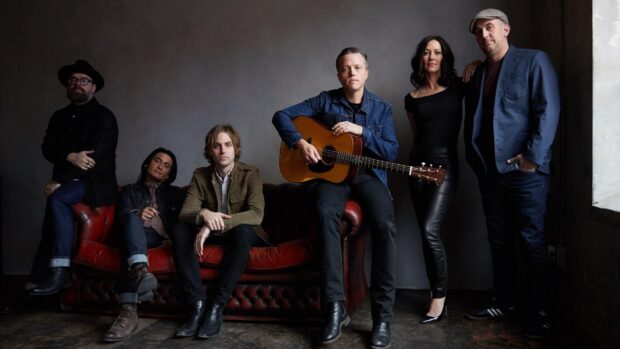 Jason Isbell and his band members posing indoors with a guitar and casual attire, HD Desktop Wallpaper