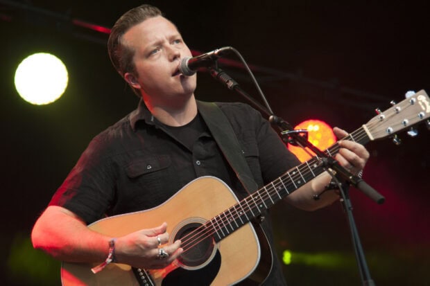 Jason Isbell is playing guitar and singing into a microphone during a concert, 2K Desktop Wallpaper