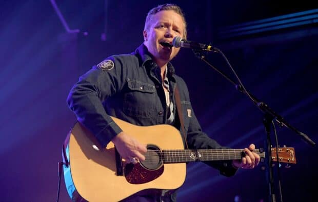 Jason Isbell is playing guitar and singing into the microphone during a concert, HD Desktop Wallpaper