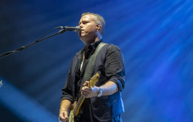 Jason Isbell is singing and playing guitar with blue stage lights, HD Desktop Wallpaper