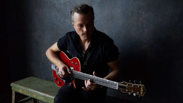 Jason Isbell is sitting on a bench playing a red Gretsch guitar in a dimly lit room, HD Desktop Wallpaper