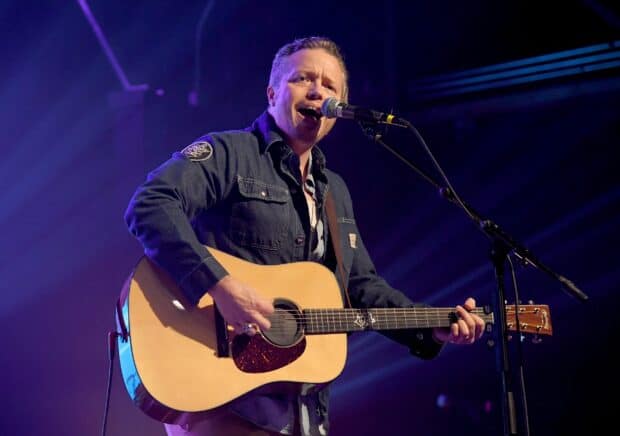 Jason Isbell is performing live on stage with his guitar and singing into a microphone, 2K Desktop Wallpaper