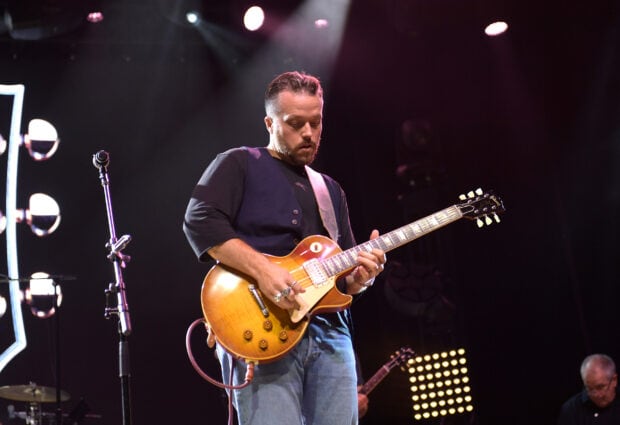 Jason Isbell is performing live playing guitar during a concert with stage lights, HD Desktop Wallpaper