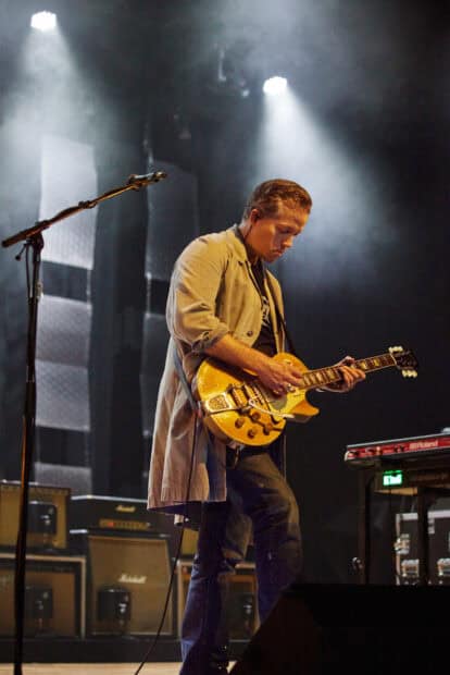 Jason Isbell is performing live while playing an electric guitar under stage lights, HD Mobile Wallpaper