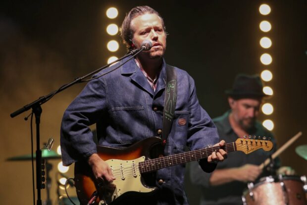 Jason Isbell is performing live with a guitar and microphone during a concert, HD Desktop Wallpaper