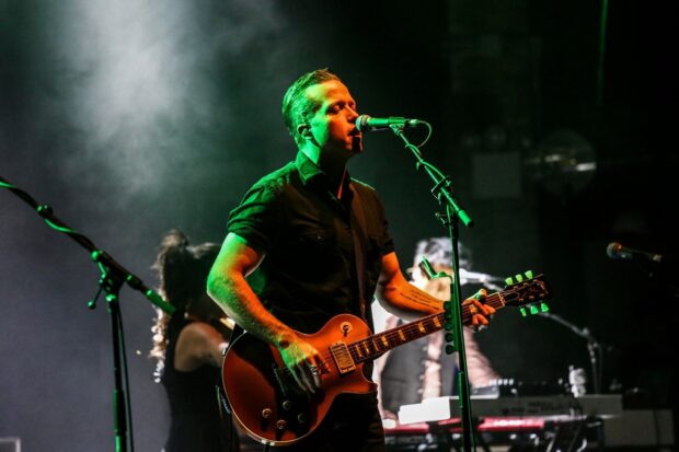 Jason Isbell performs live playing the guitar with green lighting on stage, HD Desktop Wallpaper
